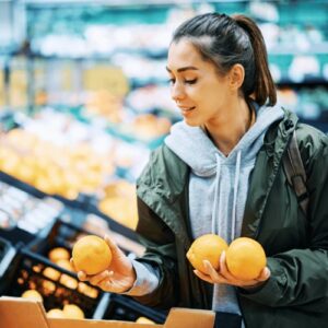 Junge Frau kauft Orangen im Supermarkt