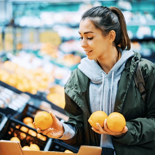 Junge Frau kauft Orangen im Supermarkt